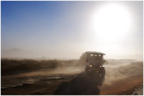 Aus einer Wand aus Sand taucht plötzlich ein Tourguide Fahrzeug auf | Namibia